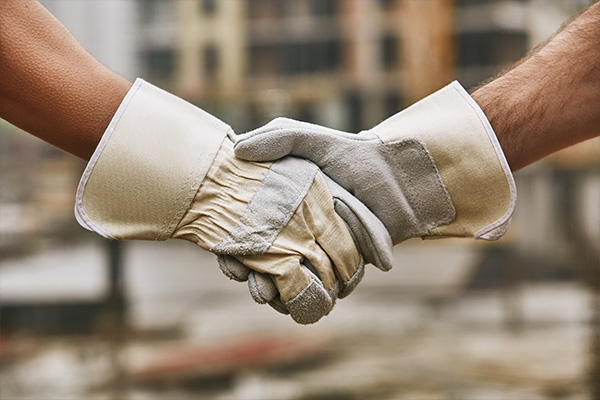 Quality Workmanship | Geer Structural Construction Construction workers shaking hands while wearing safety gloves representing quality workmanship.