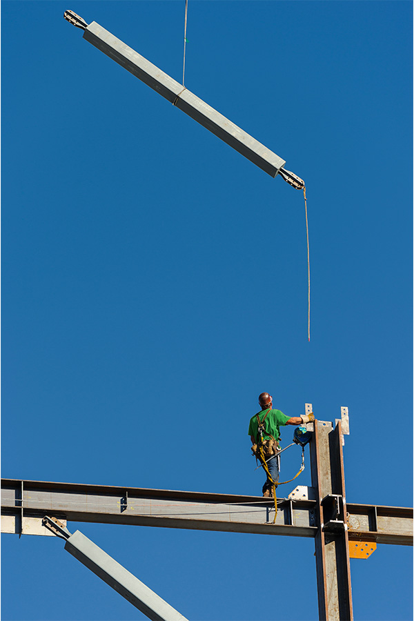 Ironworker installing structural steel beams during commercial construction.