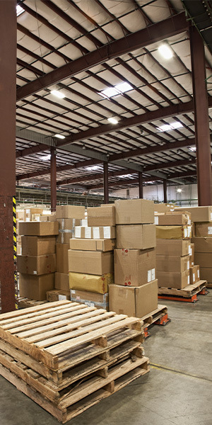 Warehouse and Distribution Center Construction | Geer Structural Construction Warehouse interior with stacked shipping boxes representing distribution center construction.